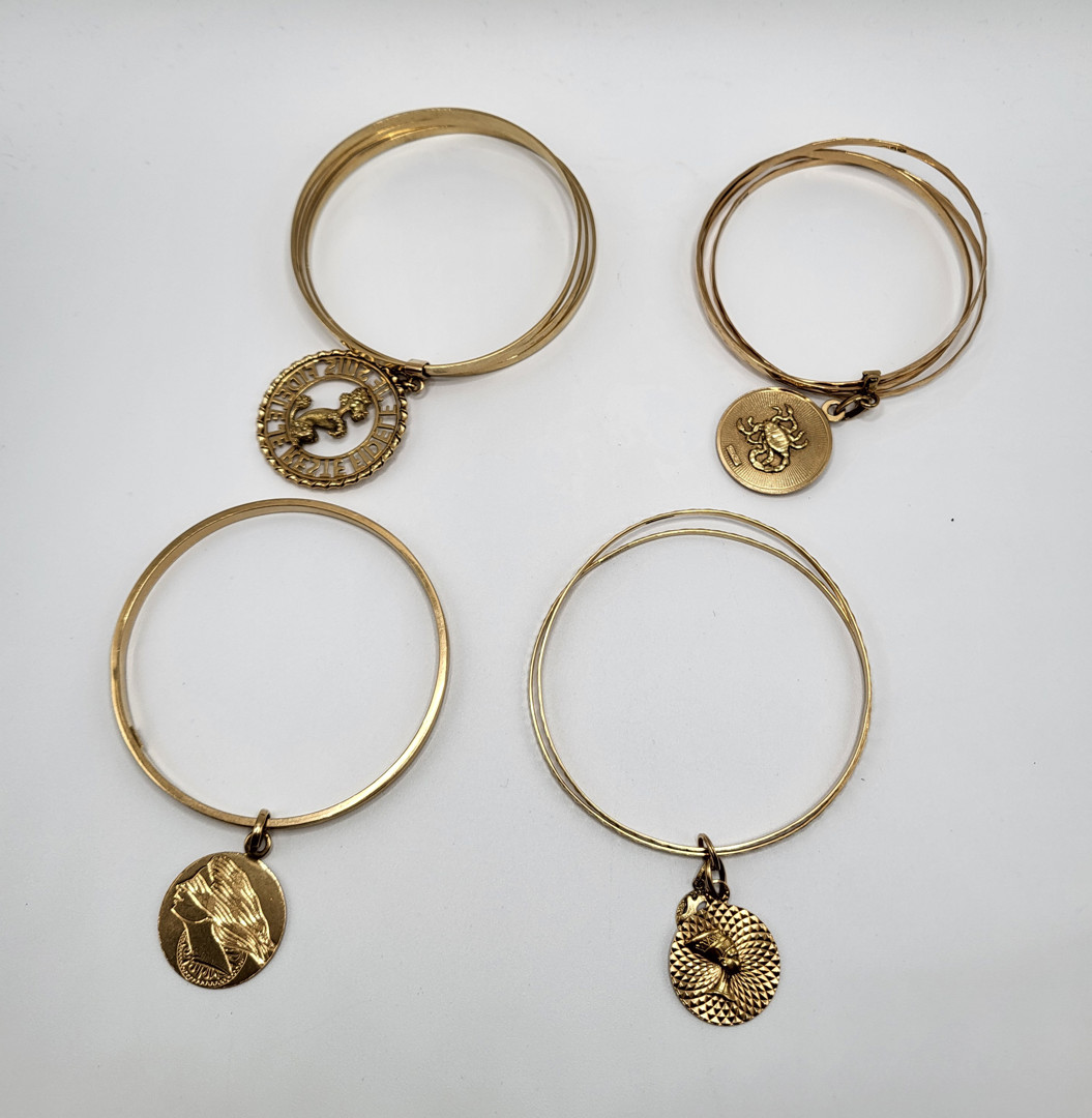 Quattro bracciali con ciondoli oro